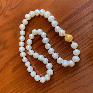 Lustrous 10 mm freshwater pearls adorn this 18  inch hand-knotted necklace with a gold fireball magnetic closure.
