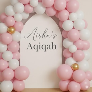 Op de afbeelding: Een decoratieve boog gemaakt van roze en witte ballonnen, met gouden accenten. De boog omlijst een witte achtergrond met de tekst "Aisha's Aqiqah" in elegant schrift, perfect voor een viering of evenement.