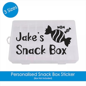Puede incluir: Una caja de aperitivos de plástico blanco con una pegatina en blanco y negro que dice "Jake's Snack Box" con un diseño de caramelo.