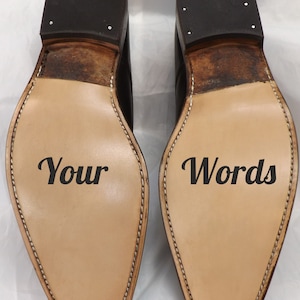 May include: A pair of brown leather shoes with the words "Your" and "Words" written on the soles.
