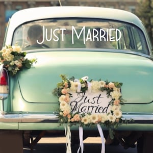Op de afbeelding: Een vintage mintgroene auto versierd met bloemstukken op de kofferbak en achterruit. De achterruit is voorzien van de witte tekst "JUST MARRIED" en een rechthoekig bord met de tekst "Just Married" omringd door bloemen.