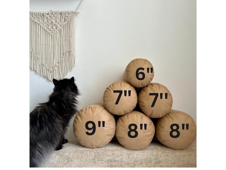 May include: A set of six brown cylindrical pillows of varying sizes. The pillows are arranged in a pyramid shape with the largest pillow at the bottom and the smallest pillow at the top. The pillows are labeled with their measurements in inches: 9", 8", 8", 7", 7", and 6".