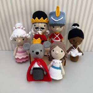 Op de afbeelding: Een set van zeven gehaakte poppen geïnspireerd door het ballet De Notenkraker. De poppen omvatten een ballerina, een notenkraker, een soldaat, een muizenkoning en drie andere personages. De poppen zijn allemaal handgemaakt en hebben ingewikkelde details.