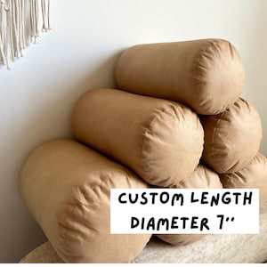 Könnte beinhalten: Ein Stapel aus vier braunen zylindrischen Kissen, jedes mit einem Durchmesser von 17,8 cm. Der Text "CUSTOM LENGTH DIAMETER 7" ist auf dem untersten Kissen aufgedruckt.