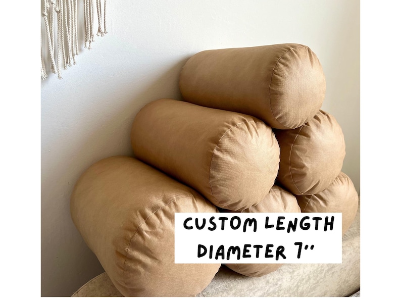 May include: A stack of four brown cylindrical pillows, each with a diameter of 7 inches. The text "CUSTOM LENGTH DIAMETER 7" is printed on the bottom pillow.