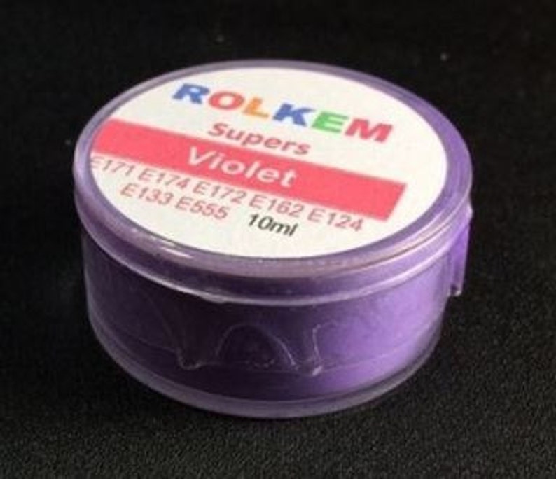 Puede incluir: Un peque&ntilde;o frasco de pl&aacute;stico transparente que contiene un polvo morado etiquetado como "Rolkem Supers Violet" con los ingredientes E171, E174, E172, E162, E124, E133 y E555. El frasco est&aacute; etiquetado con un volumen de 10 ml.