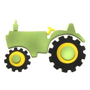 Puede incluir: Un tractor de juguete verde con ruedas negras y llantas amarillas. El tractor está hecho de fieltro o espuma y tiene un diseño simple.