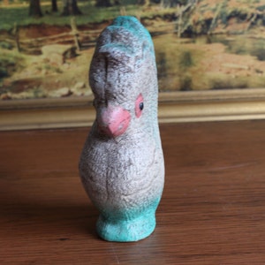 May include: A vintage bird figurine with a textured, speckled gray body, a pink beak, and a turquoise base and head crest. The bird has a single black eye. The figurine is likely made of ceramic or a similar material.