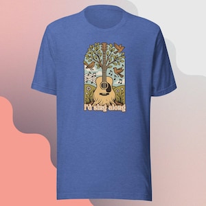 Op de afbeelding: Blauw T-shirt met een gitaarontwerp, een boom, vogels en muzieknoten. De tekst "I'd sing along" staat onder de gitaar. Het ontwerp gebruikt bruine, groene en beige kleuren.