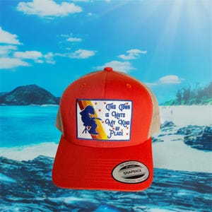 Peut inclure: Casquette de camionneur rouge avec un dos en filet beige et un écusson avec l'inscription "This Town is Nuts My Kind of Place". L'écusson représente une silhouette bleue d'une personne jouant d'un instrument. La casquette a une visière incurvée et une fermeture à pression.