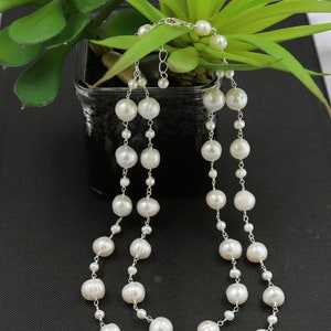 May include: A double strand pearl necklace with silver chain links. The pearls are white and round.