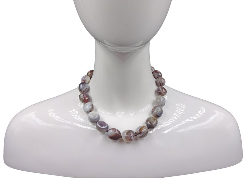 Puede incluir: Un collar hecho de cuentas de &aacute;gata marr&oacute;n y blanca. Las cuentas son de forma ovalada y tienen un acabado natural y pulido.