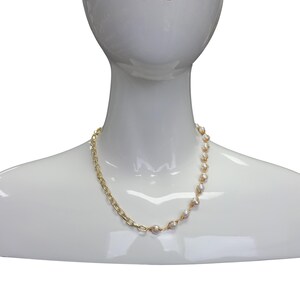 May include: A gold chain necklace with white pearl accents. The necklace is asymmetrical, with the chain on one side and the pearls on the other.