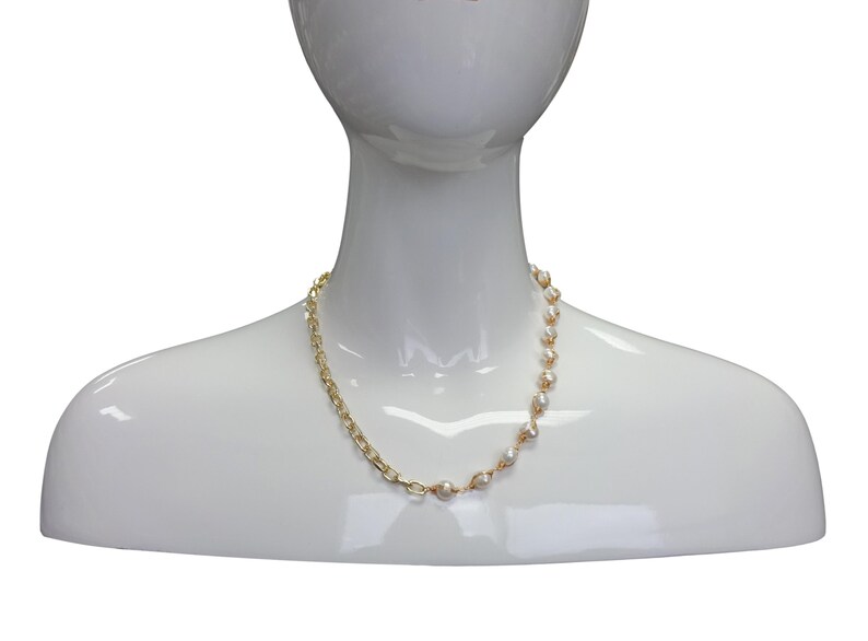 May include: A gold chain necklace with white pearl accents. The necklace is asymmetrical, with the chain on one side and the pearls on the other.