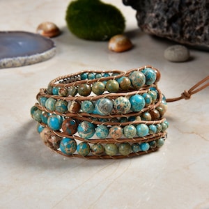 May include: A multi-strand wrap bracelet featuring brown leather cord and turquoise and brown jasper beads.
