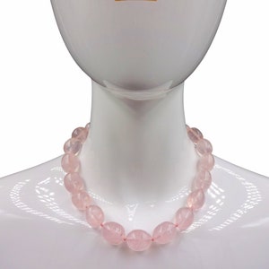 Puede incluir: Un collar de cuentas de cuarzo rosa sobre un maniqu&iacute; blanco. El collar est&aacute; hecho de cuentas lisas de forma ovalada.