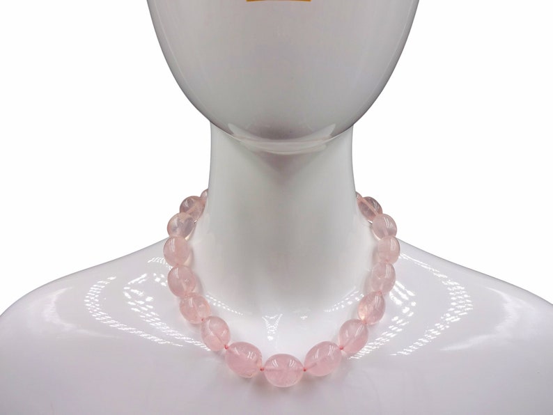Puede incluir: Un collar de cuentas de cuarzo rosa sobre un maniqu&iacute; blanco. El collar est&aacute; hecho de cuentas lisas de forma ovalada.