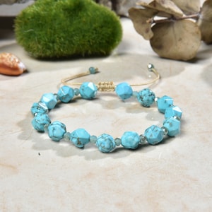 May include: A turquoise gemstone bracelet with a knotted cord closure. The bracelet features faceted turquoise beads and smaller clear beads.