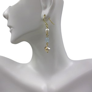 May include: Gold dangle earrings with a white pearl, light blue beads, and a clear crystal.