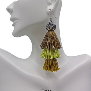 May include: A pair of long, multi-coloured tassel earrings with a crystal-encrusted ball at the top. The tassels are brown, green, and gold.