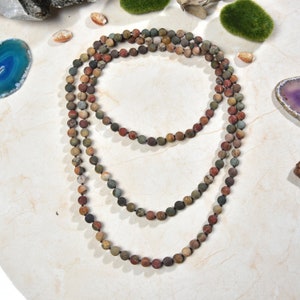 May include: A multi-strand necklace made of brown, red, and green gemstone beads. The beads are round and have a natural, polished finish.