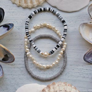 Set van drie armbanden. Grijze, zwart-witte armband. Heishi-armband. Parelarmband met stretch. Trendy stapel van 3 stretcharmbanden