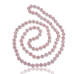May include: A long strand of pink rose quartz beads, strung together on a clear thread. The beads are round and smooth, and the necklace is coiled into a spiral shape.