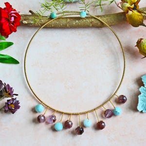 May include: A gold wire choker necklace with a row of dangling blue and purple gemstone beads.