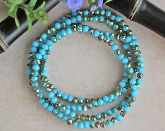 May include: A turquoise and iridescent blue crystal bead necklace. The necklace is made of multiple strands of beads and is wrapped around a bamboo stick.