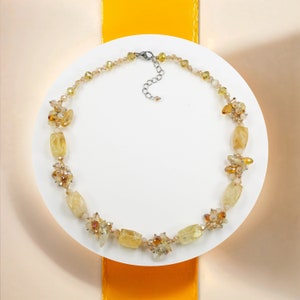 May include: A yellow and gold necklace with a silver clasp. The necklace is made of small, faceted stones and beads.