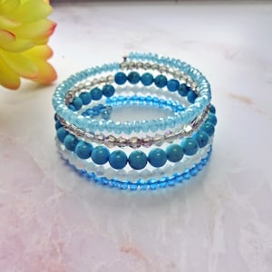 May include: A multi-strand bracelet with turquoise and light blue beads. The bracelet is made of several layers of beads, with the turquoise beads being the largest.