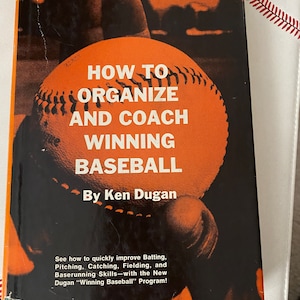 May include: A vintage orange and black book titled "How to Organize and Coach Winning Baseball" by Ken Dugan. The cover features a baseball with white stitching.