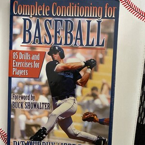 May include: A book titled "Complete Conditioning for Baseball" featuring a baseball player in action. The cover includes text about drills and exercises for players, with a foreword by Buck Showalter. Authors are Pat Murphy and Jeff Forney.