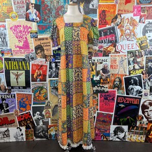 Könnte beinhalten: Ein langes Patchwork-Kleid mit quadratischem Ausschnitt und kurzen Ärmeln. Das Kleid ist aus einem bunten Stoff mit verschiedenen floralen und geometrischen Mustern gefertigt. Das Kleid hat einen Spitzenbesatz am Saum.