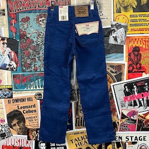 Puede incluir: Un par de pantalones de pana azul con corte recto. Los pantalones tienen una etiqueta de la marca Levi's en el bolsillo trasero con el texto "Straight Leg Boys Slim Fit".