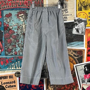 Vintage toddler kids boys 50s-60s blue grey and white striped seersucker elastic waist wide leg pajama pants. There is no label or tag size. We estimate it to fit kids size 3T. Rock th em as trousers! Has a stain on the front right, but are in otherwise good, pre-owned condition. Feels like a rayon blend, but am not certain of fabric content. So many ways to style!