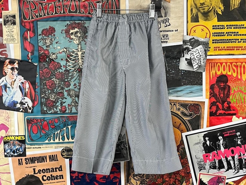 Vintage toddler kids boys 50s-60s blue grey and white striped seersucker elastic waist wide leg pajama pants. There is no label or tag size. We estimate it to fit kids size 3T. Rock th em as trousers! Has a stain on the front right, but are in otherwise good, pre-owned condition. Feels like a rayon blend, but am not certain of fabric content. So many ways to style!