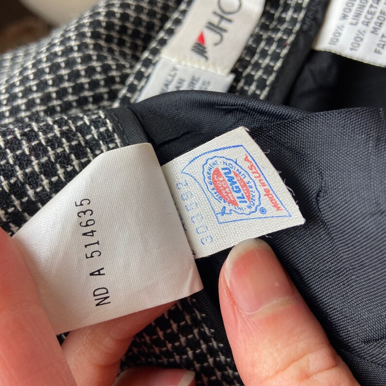 Pode incluir: Tecido xadrez preto e branco com uma etiqueta branca que diz "ND A 514635" e uma etiqueta azul e branca com o texto "ILGWU" e "Made in USA".