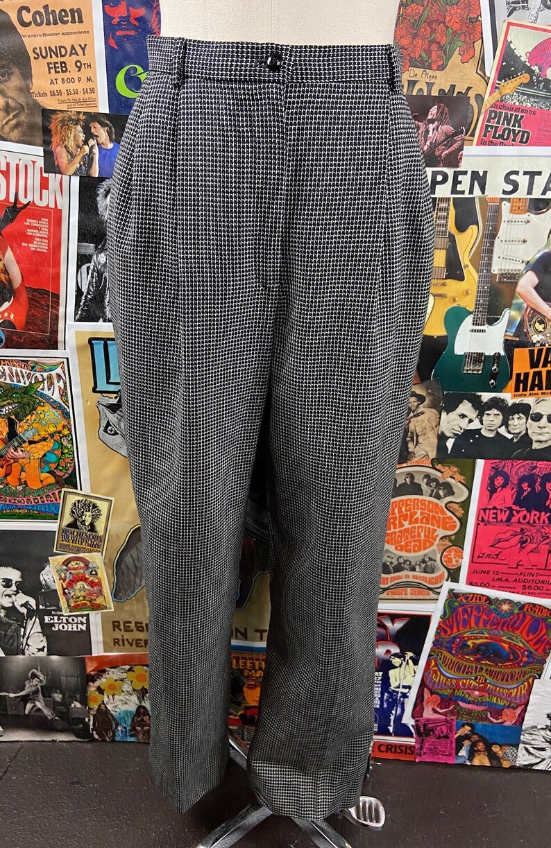 Pode incluir: Cal&ccedil;a de xadrez preto e branco de cintura alta e fecho de bot&atilde;o. A cal&ccedil;a tem perna reta e &eacute; feita de um tecido leve.