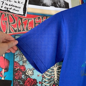 K&ouml;nnte beinhalten: Ein kurz&auml;rmliges T-Shirt in Royalblau mit einem grafischen Druck. Der Druck zeigt ein farbenfrohes Design mit einem Skelett und Blumen.