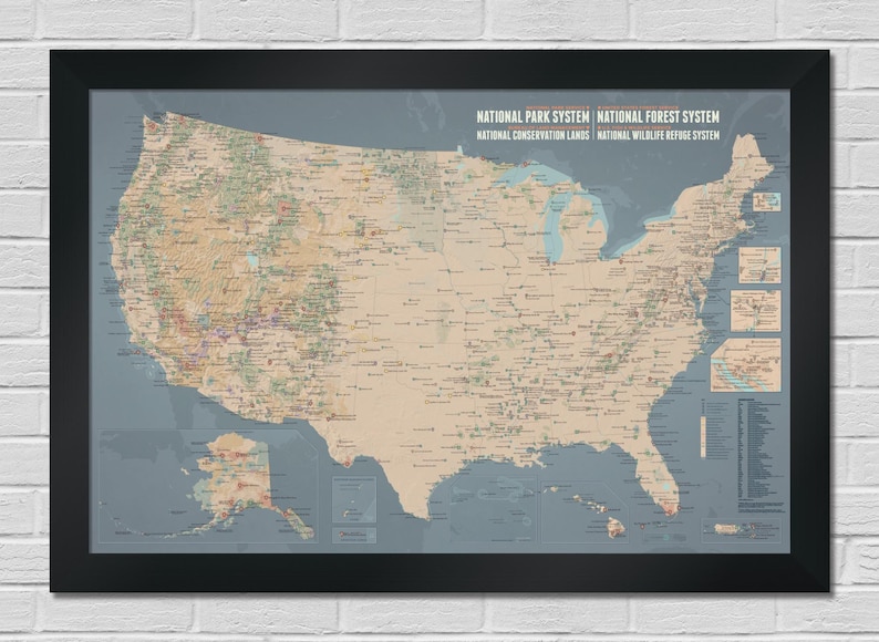 May include: A framed map of the United States, showcasing national parks, forests, and conservation areas. The map features a detailed depiction of the country's geography, with various colors and symbols indicating different locations. The frame is black.