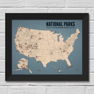 May include: Framed map of the United States National Parks. The map is in a black frame, with a blue-grey background. The map itself is a beige colour, with red pin markers indicating the locations of the parks. The text "NATIONAL PARKS OF THE UNITED STATES" is at the top.