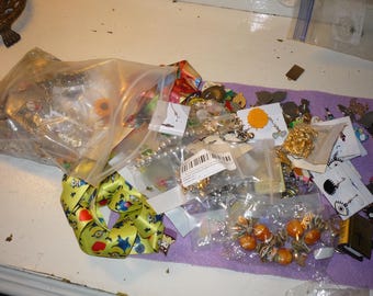 May include: A clear plastic bag filled with a variety of colorful jewelry, including necklaces, earrings, and charms. The jewelry is arranged on a purple surface with a white background.