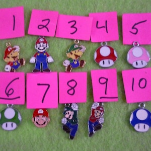 May include: Ten different charms featuring characters from the Super Mario Bros. video game franchise. The charms are numbered 1 through 10 on pink sticky notes. The charms include Mario, Luigi, and Toad characters, as well as red, pink, green, and blue mushrooms.