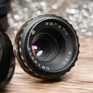 May include: A black camera lens with the text "BELARUS 2120" and "N 8155" printed on the side.