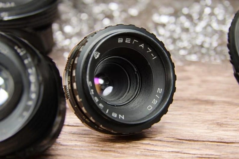 May include: A black camera lens with the text "BELARUS 2120" and "N 8155" printed on the side.