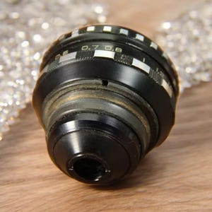 May include: A black camera lens with a silver ring and markings that read "0.7 0.8".