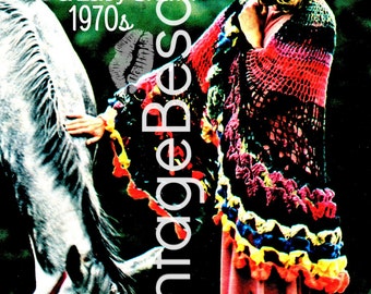 May include: A woman wearing a colorful crocheted shawl with a ruffled edge, standing in a field with a white horse. The shawl is made with a cobweb stitch and has a variety of colors, including red, yellow, blue, and green. The text "Crochet a Color Cobweb for a Lacy Shawl 1970s" is visible at the top of the image.