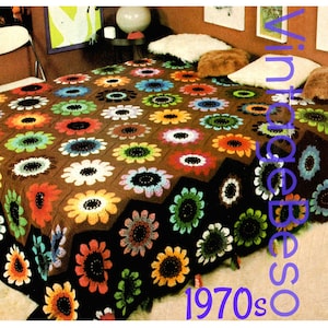 May include: A brown crocheted blanket with a floral pattern in shades of green, orange, yellow, and blue. The blanket is laid out on a bed with pillows and a side table.