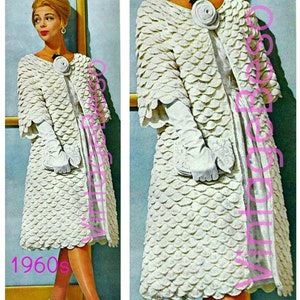 May include: A white crochet coat with a large white flower brooch. The coat is made of a textured fabric that resembles scales. The model is wearing white gloves and a white dress. The image is from the 1960s.